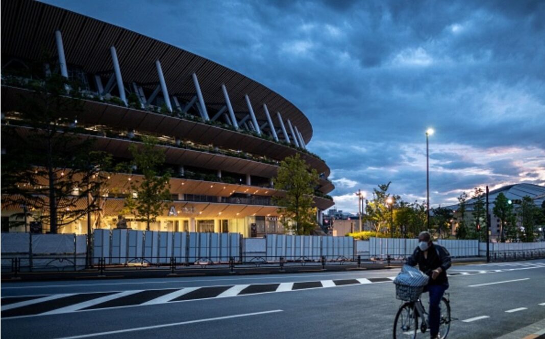 A man rides his bike near the National Stadium, main venue for the Tokyo 2020 Olympic and Paralympic Games in Tokyo on May 17, 2021. (Photo by Philip FONG / AFP) (Photo by PHILIP FONG/AFP via Getty Images)