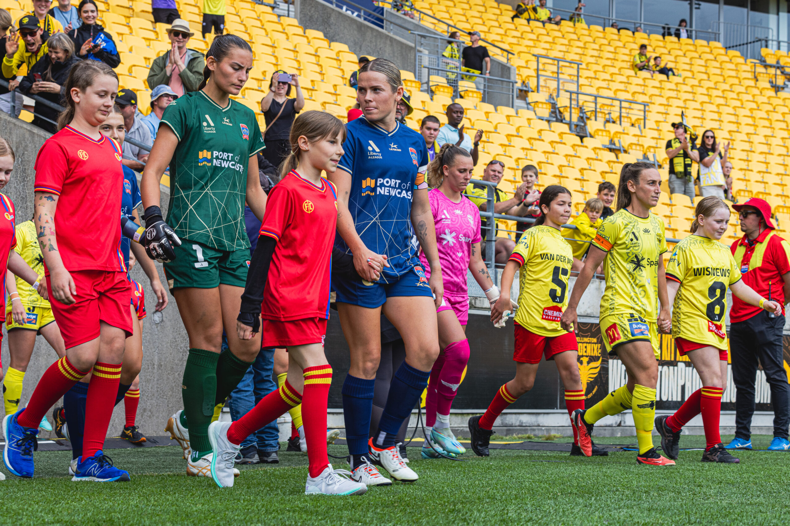 Wellington Phoenix and Newcastle Jets walk onto the field with player mascots, ahead of their A-League Women game played at Sky Stadium on December 23, 2023. Photo Credit: James Foy (Instagram - @natural_lightphotogram)